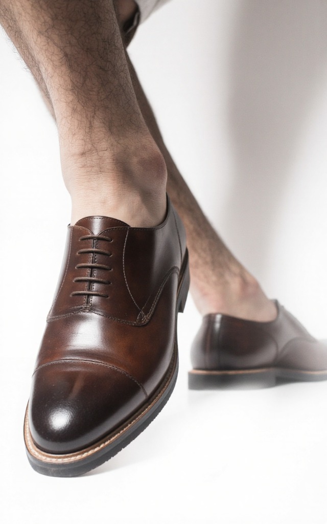 A male model wearing Derby shoes, against a white background, with a close   up of the feet